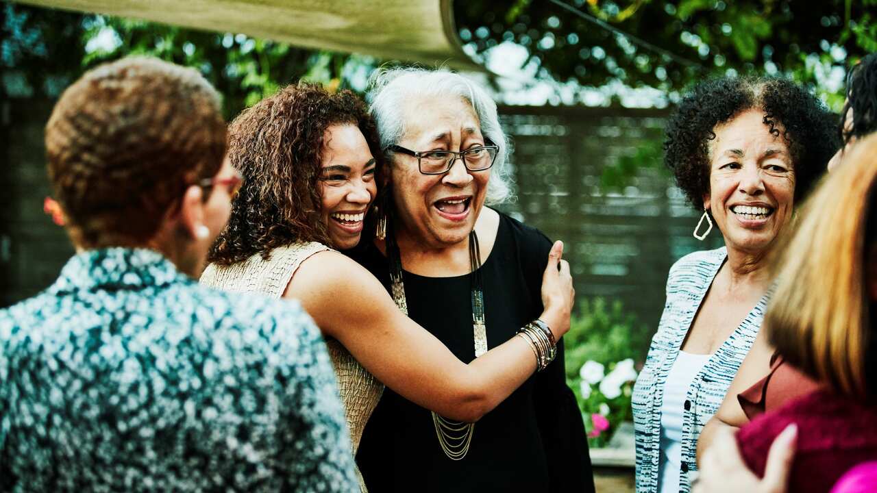 Mature daughter embracing senior mother after outdoor family dinner party