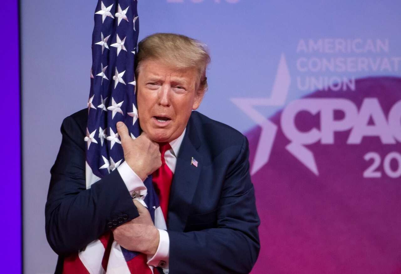 US President Donald J. Trump hugs a US flag before speaking at the 46th annual Conservative Political Action Conference (CPAC). 