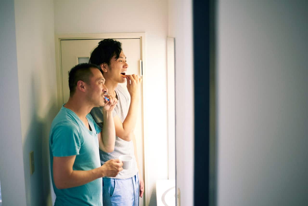 Two Asian men brushing their teeth
