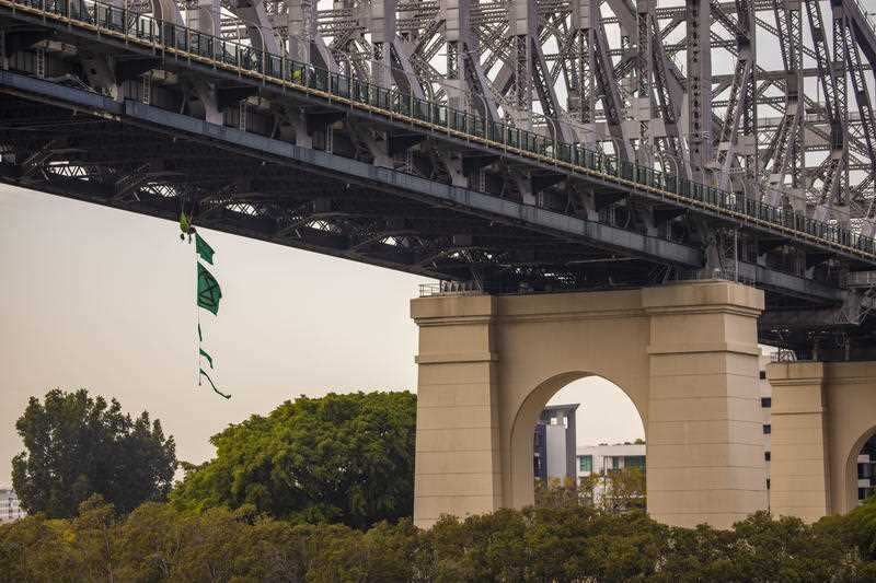 An activist from Extinction Rebellion dangles from the Story Bridge in a hammock as part of protests in Brisbane, Tuesday, October 8, 2019.