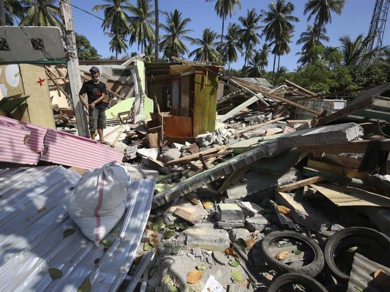 A man walks around his house damaged in the Lombok quake