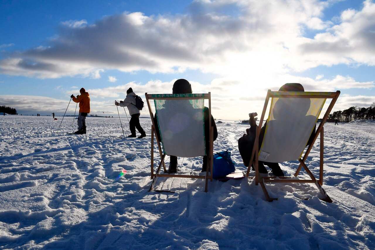 People enjoying sunny winter day on ice on waterfront of Helsinki, Finland on February 14, 2021. 