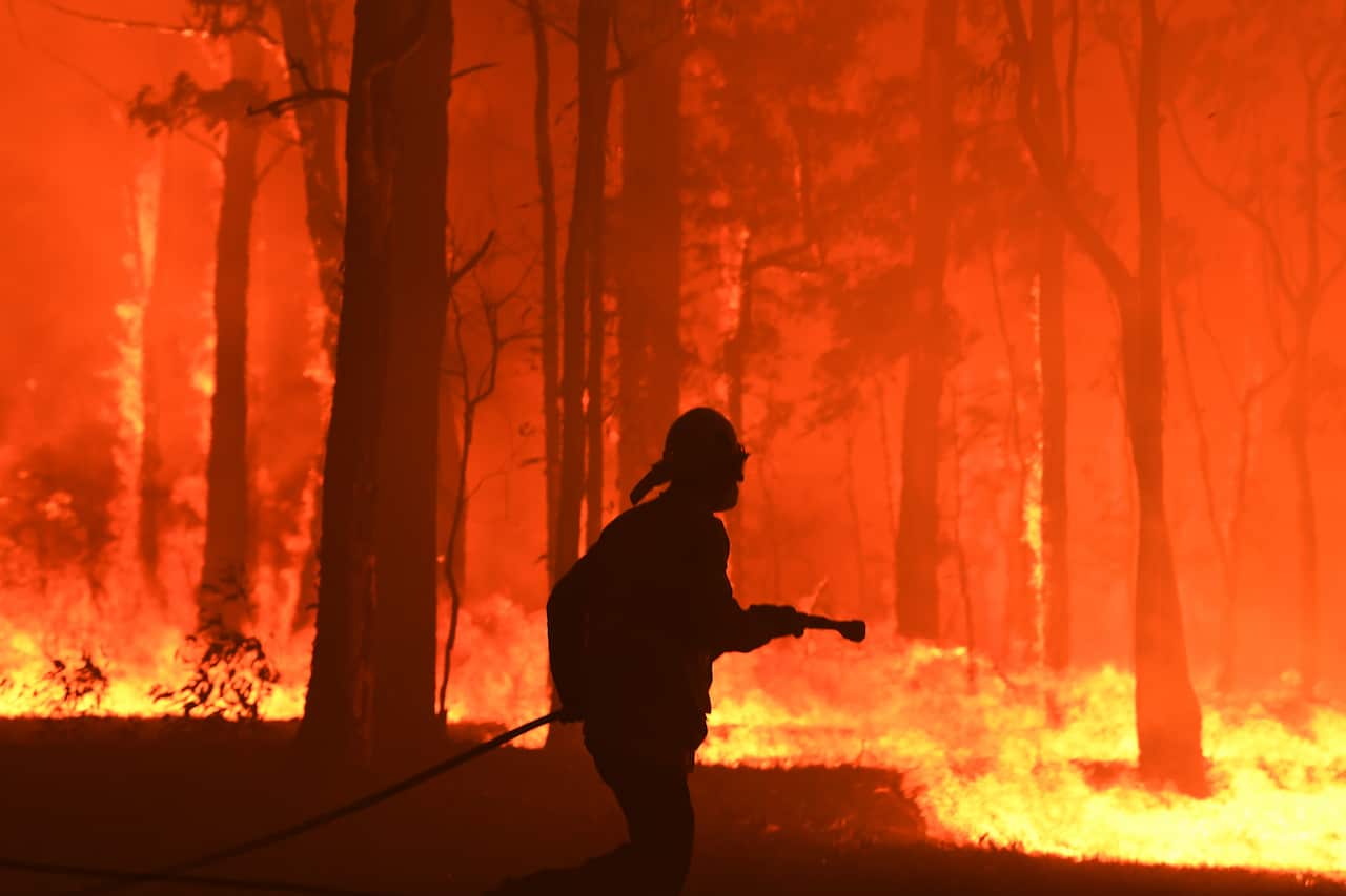 RFS volunteers and NSW Fire and Rescue officers protect a home on Wheelbarrow Ridge Road near Colo Heights, south-west of Sydney.