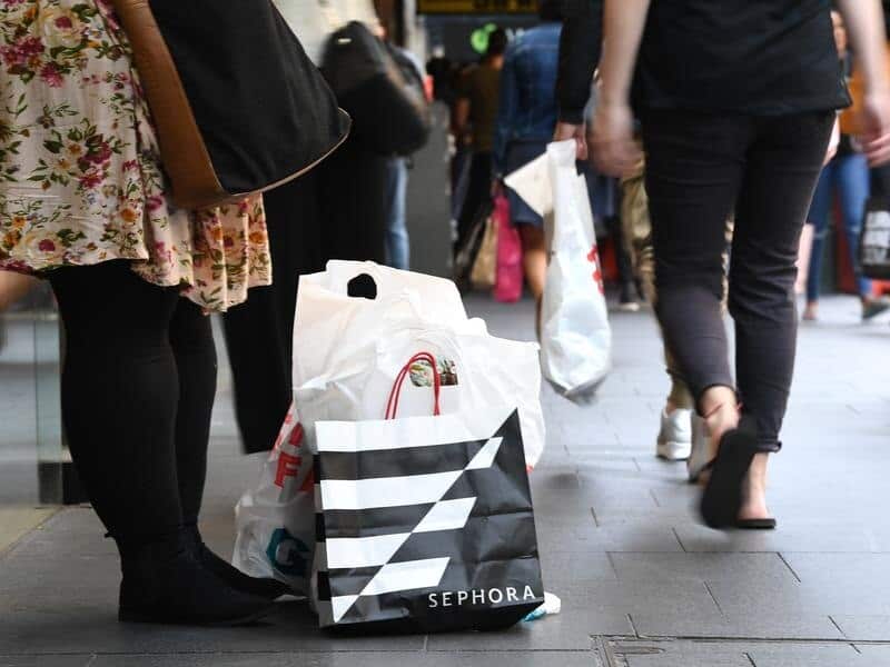 Shopping bags surrounded by people walking on street.