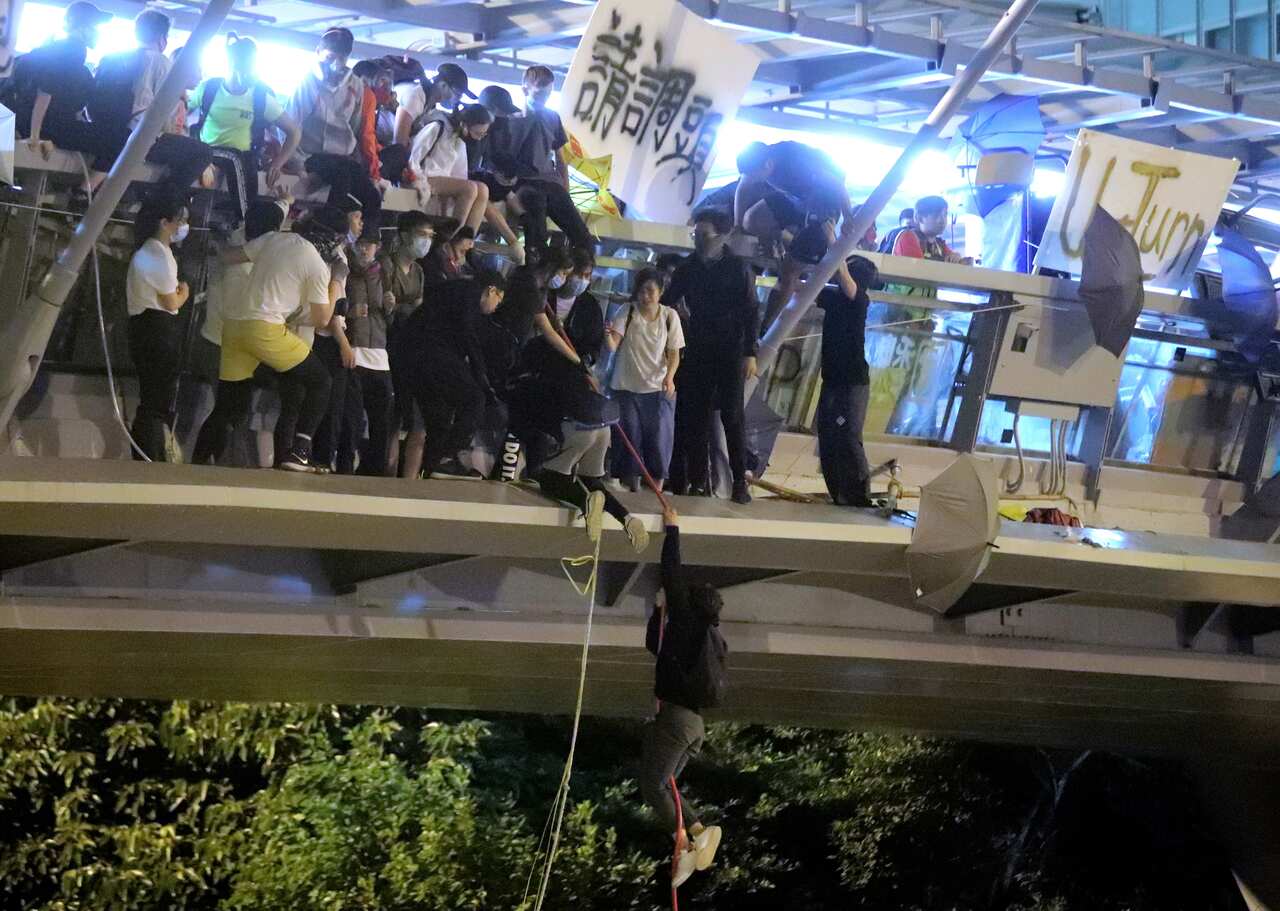 Protestors use a rope to lower themselves from a pedestrian bridge to waiting motorbikes in order to escape from Hong Kong Polytechnic University.