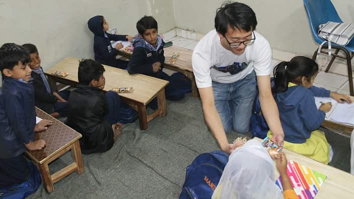 Australian volunteer teacher, Martin Chia distributing biscuits to school children in Karachi.