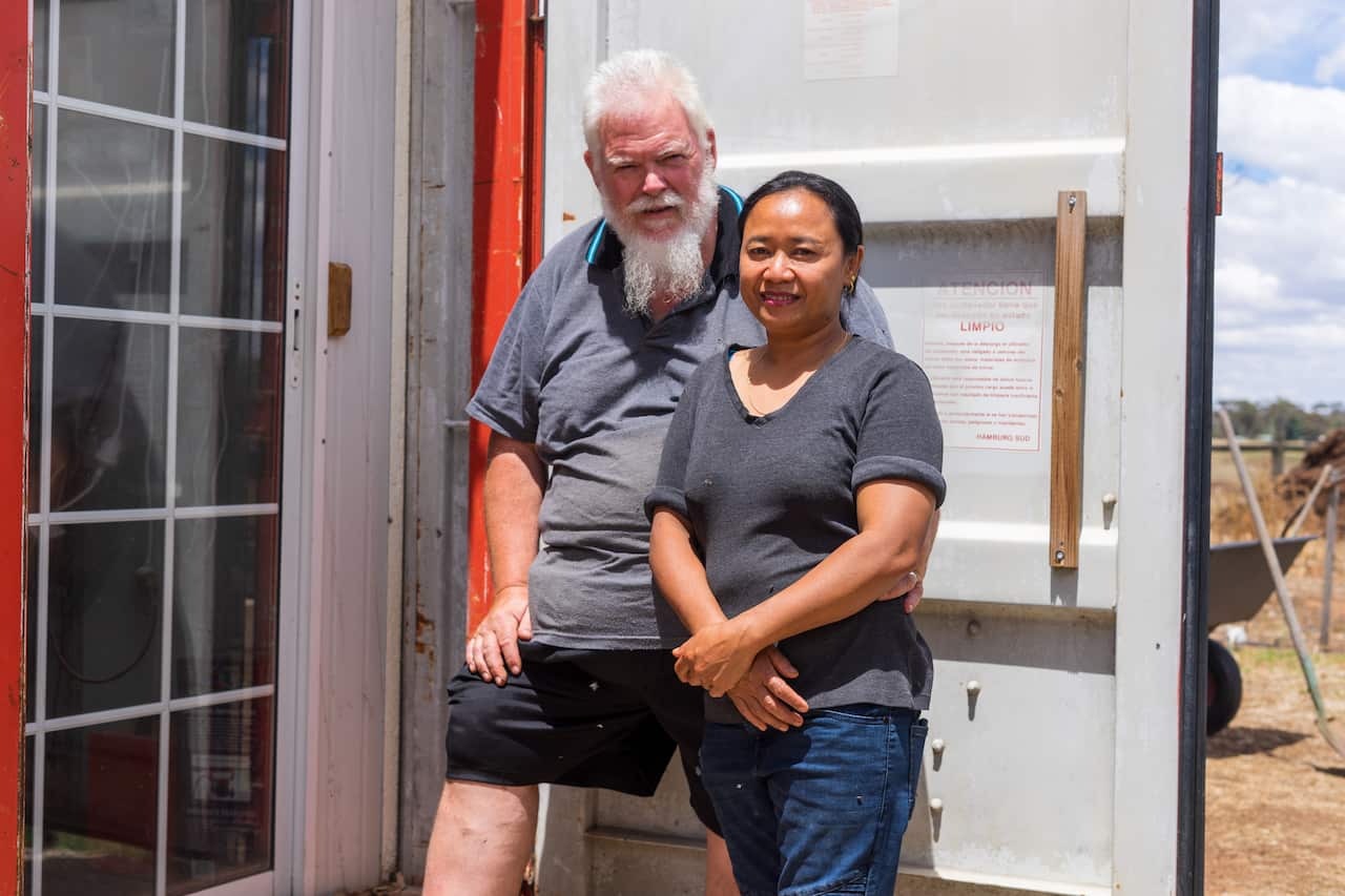 คุณพรทิพย์ ชื่นชอบ และคุณสตีเฟน สเตบบิง สามี อยู่หน้าตู้คอนเทนเนอร์ที่ดัดแปลงเป็นโรงเลี้ยงจิ้งหรีด