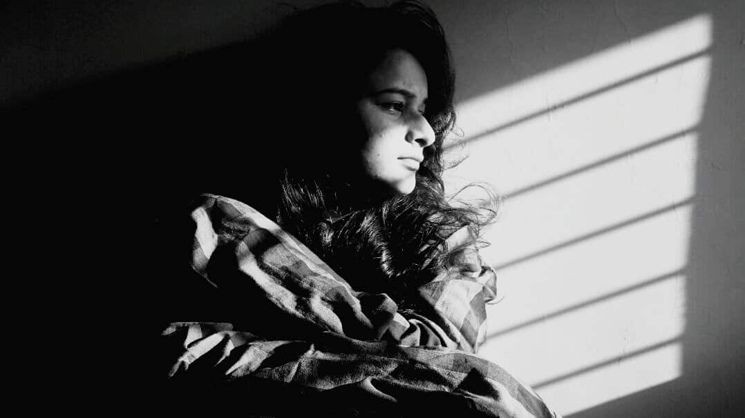 Depressed Woman Looking Away While Sitting In Darkroom