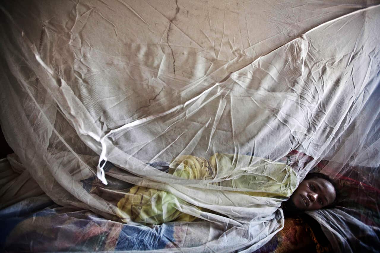 A woman suffering from malaria rests on a bed at a hospital in El Sereif village, North Darfur, Sudan.
