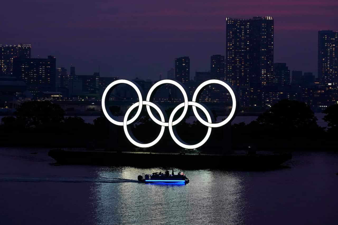 The Olympic rings float in the water at sunset in Tokyo.