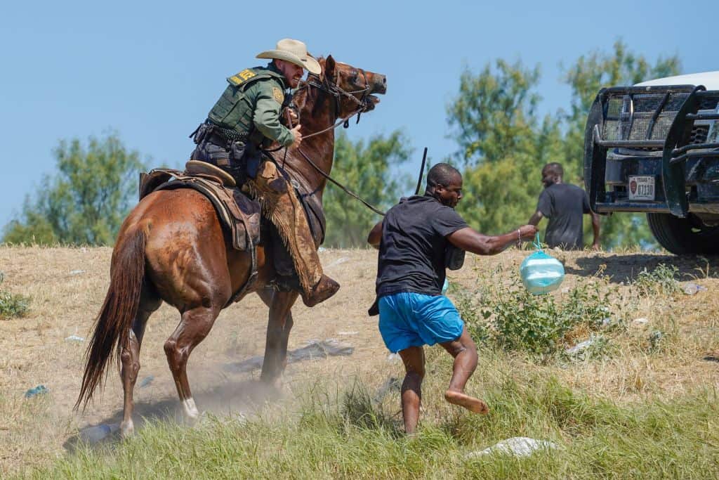 A United States Border Patrol agent on horseback uses the reins to try and stop a migrant from entering an encampment on the banks of the Rio Grande in Texas.