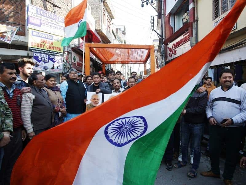 Indian people wave the national flag as they celebrate the air strikes