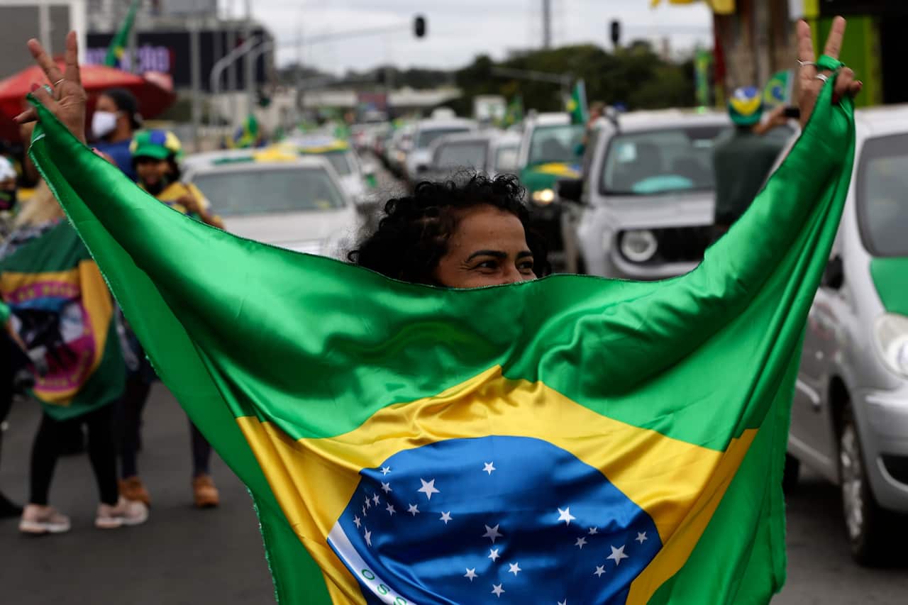 A supporter of Brazil's President Jair Bolsonaro, holding a national, dances during a protest. 