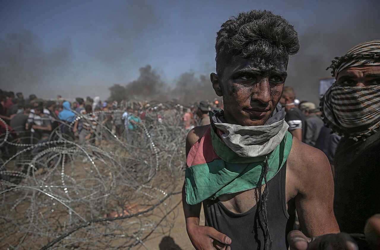 Palestinians protesters pulling barbed wire fence installed by Israeli army along the border during clashes after protests near the border with Israel
