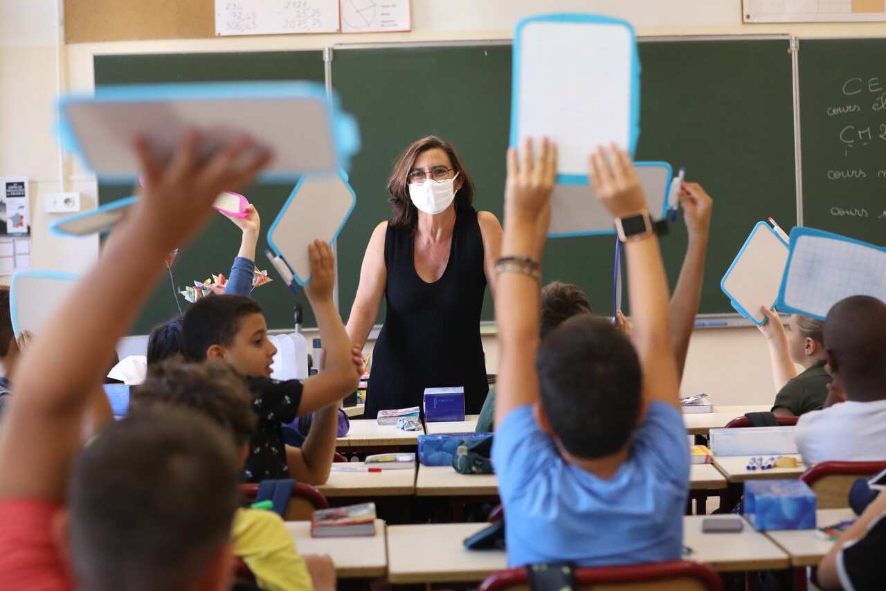 A teacher wearing a protective mask teaches in her classroom on the first day of the new school year in Nice, France.