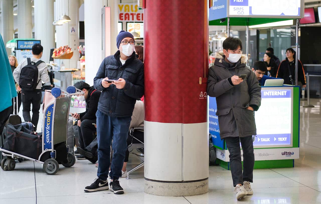 People wearing medical masks wait for arriving passengers at John F. Kennedy international airport in New York.