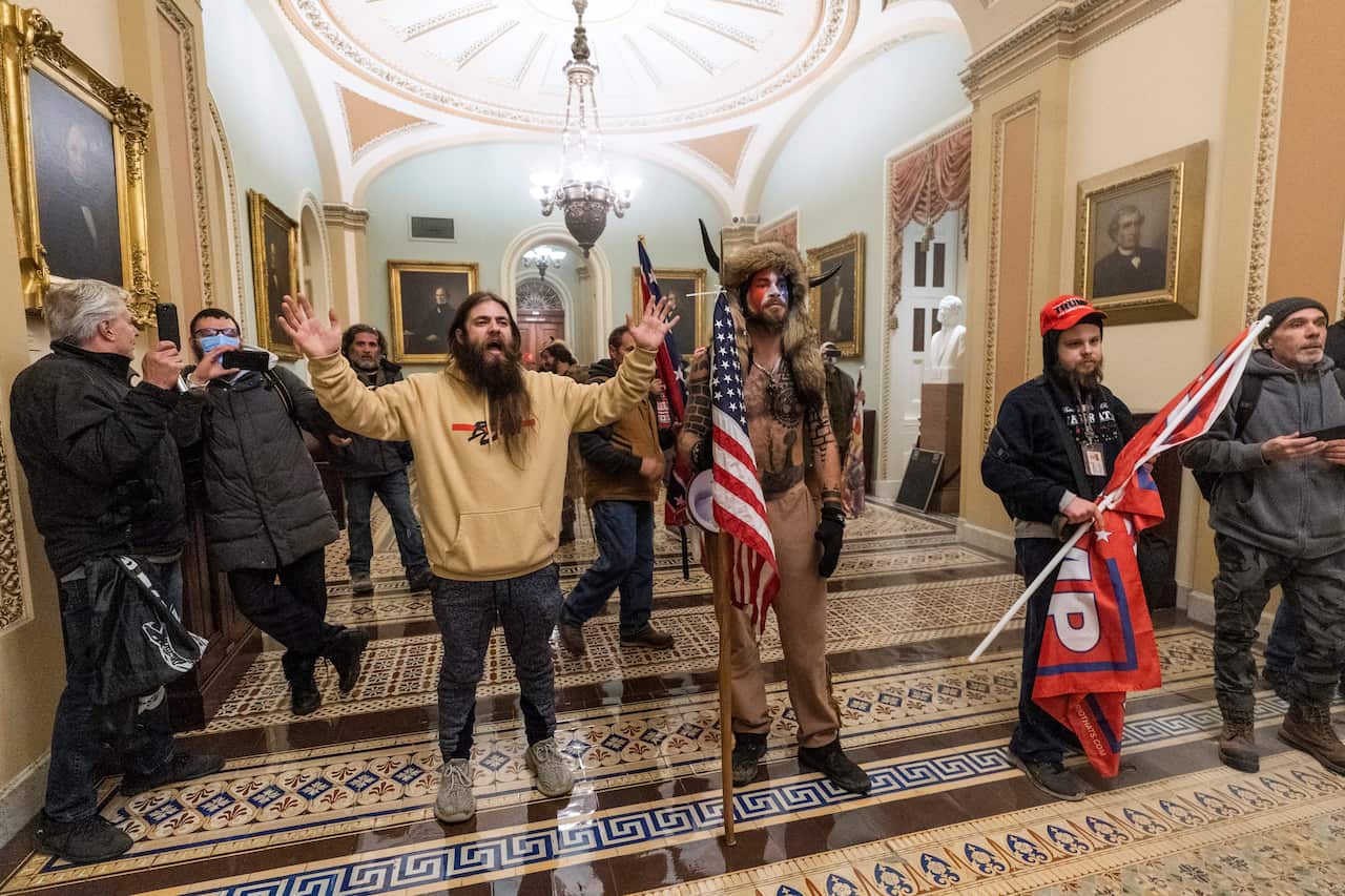 Jake Angeli (centre) - known online as the ‘Q Shaman’ - pictured inside the Capitol.