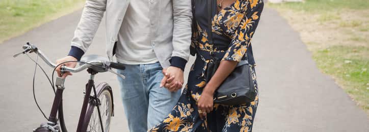 Couple walking with bicycle in park