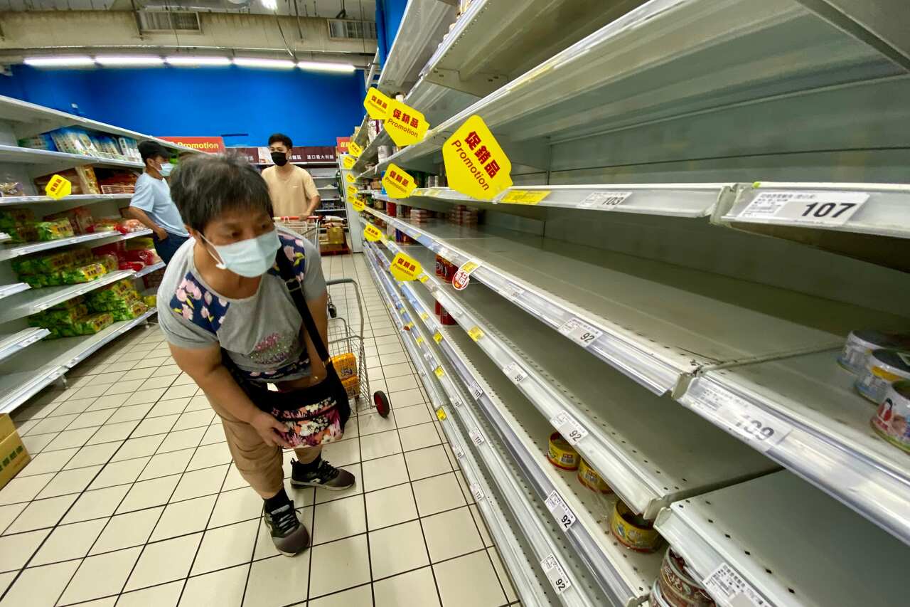 A woman checks an almost empty shelf as residents rushed to buy grocery essentials inside a supermarket in Taipei, Taiwan, 17 May 2021.