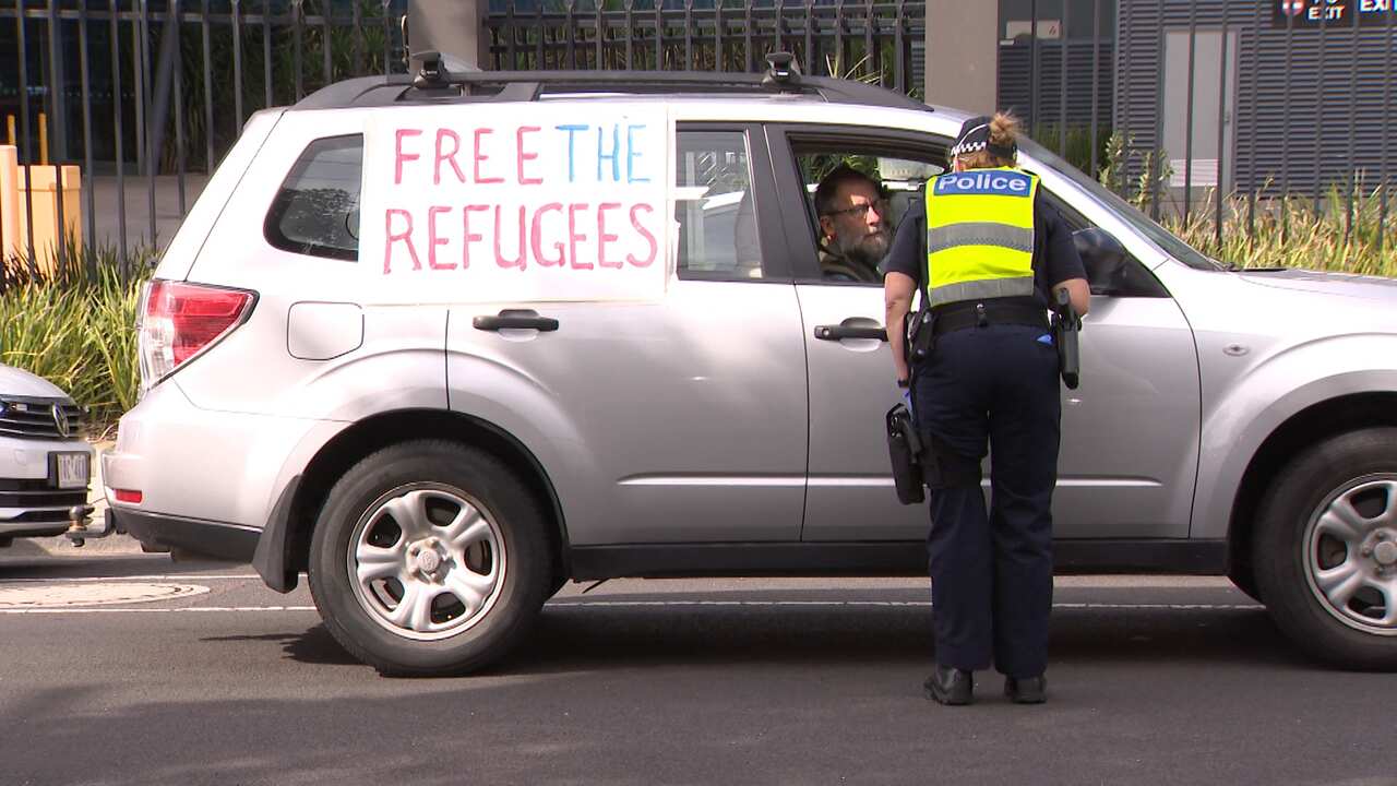 Police question a protester outside the Mantra Hotel in Melbourne. 