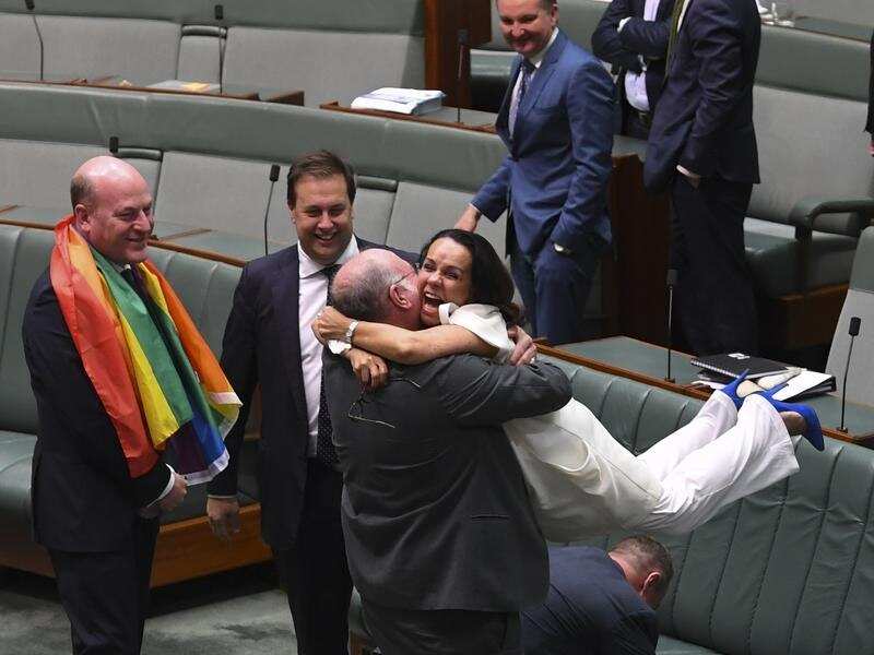 Liberal MP Warren Entsch lifts Labor MP Linda Burney in celebration.