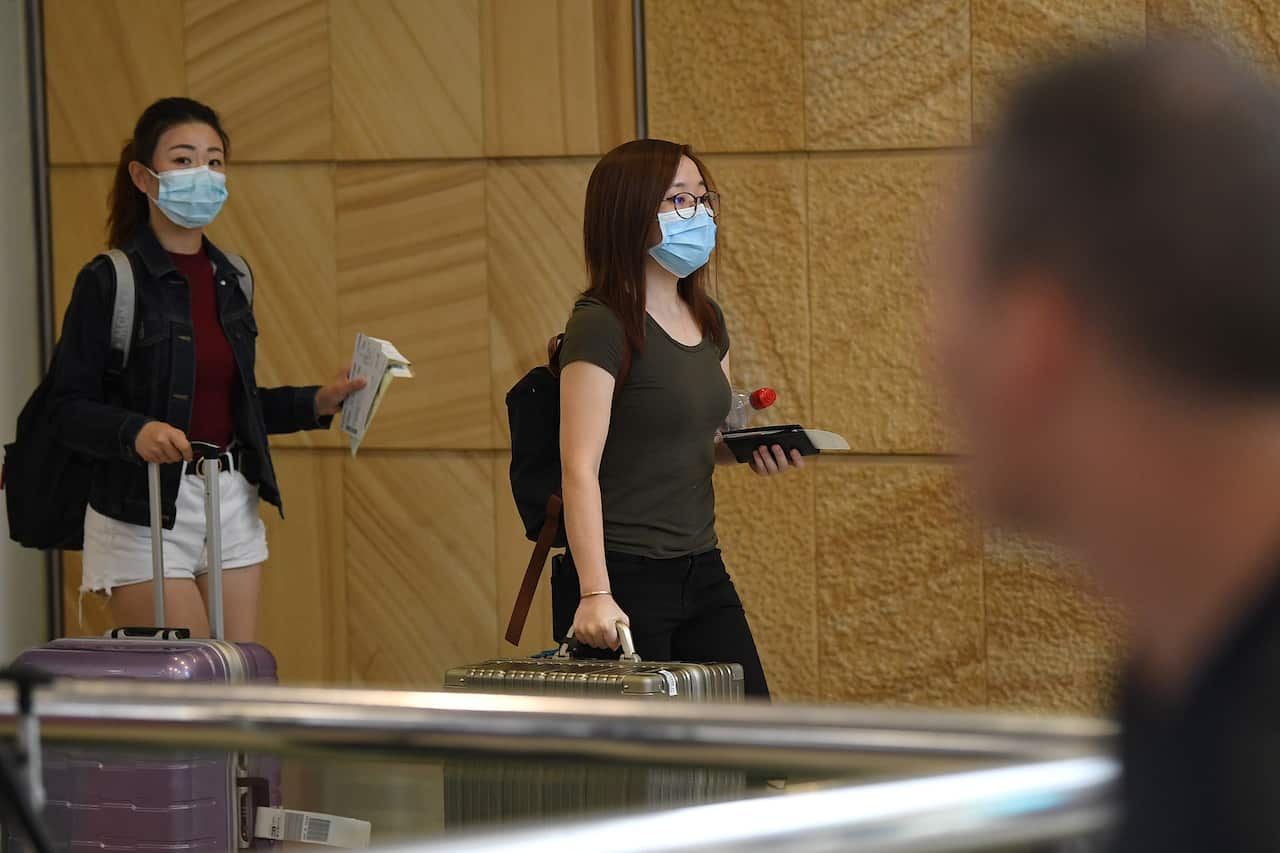 Passengers wearing protective masks arrive at Sydney International Airport.