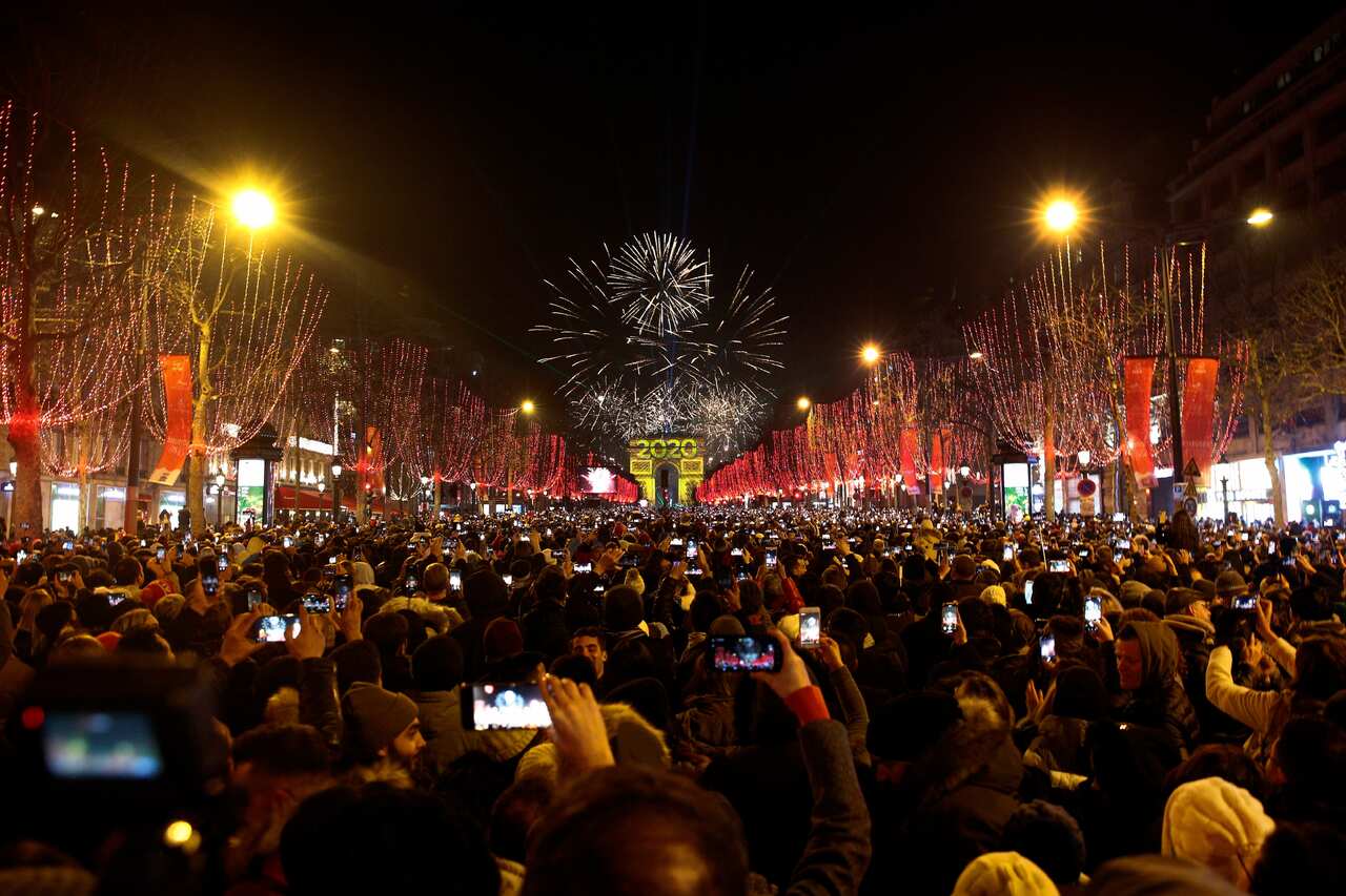 Revellers photograph fireworks over the Arc de Triomphe as they celebrate the New Year on the Champs Elysees, in Paris, France, Wednesday, Jan. 1, 2020. (AP Photo/Christophe Ena)