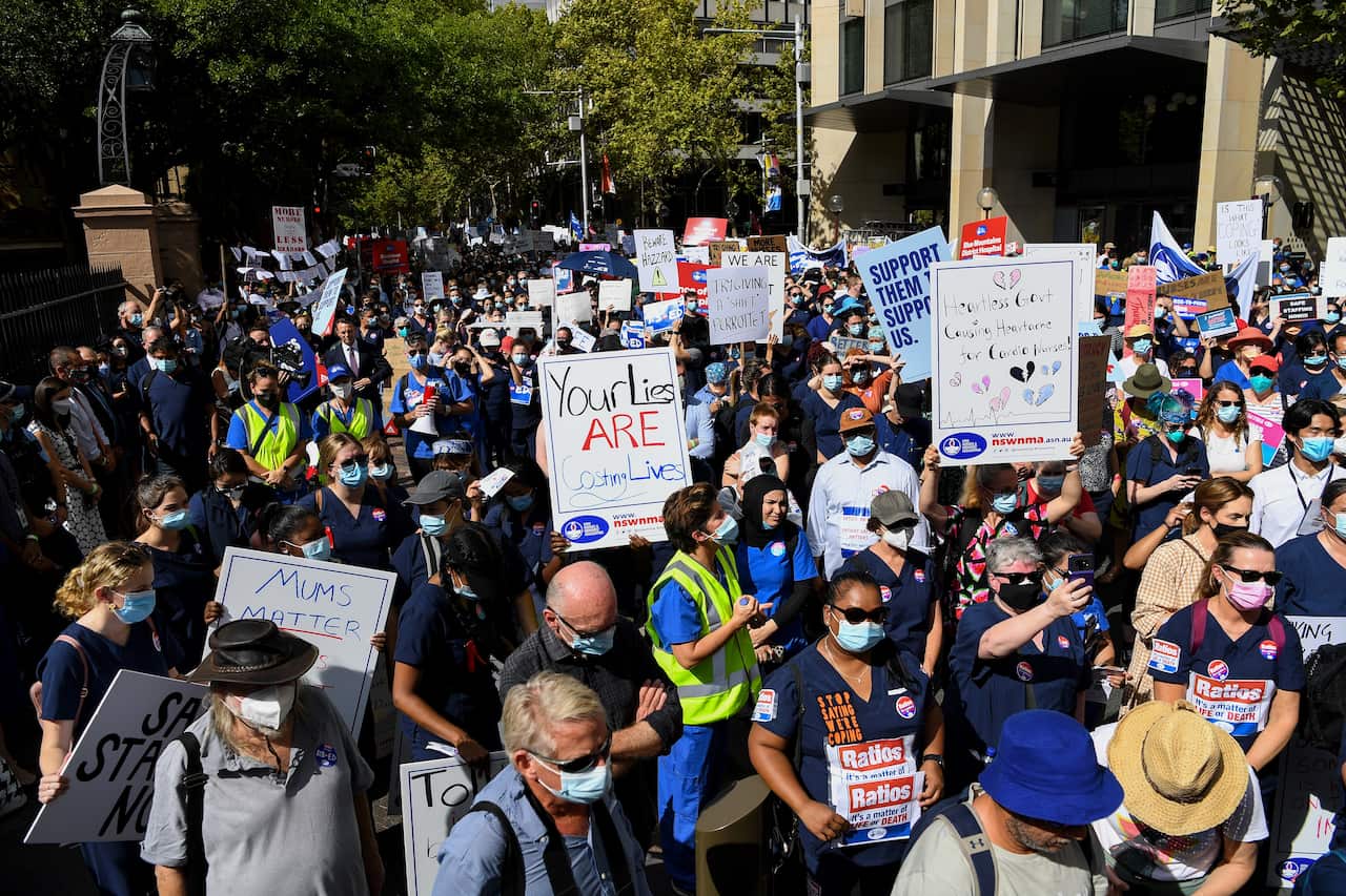 Nurses hold placards during a nurses’ strike outside the NSW Parliament House in Sydney, Tuesday, February 15, 2022. NSW public hospital nurses are on strike over understaffing frustrations, pay and conditions. (AAP Image/Bianca De Marchi) NO ARCHIVING