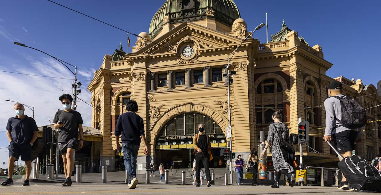 People are seen walking across Flinders Street in Melbourne, Friday, October 22, 2021.