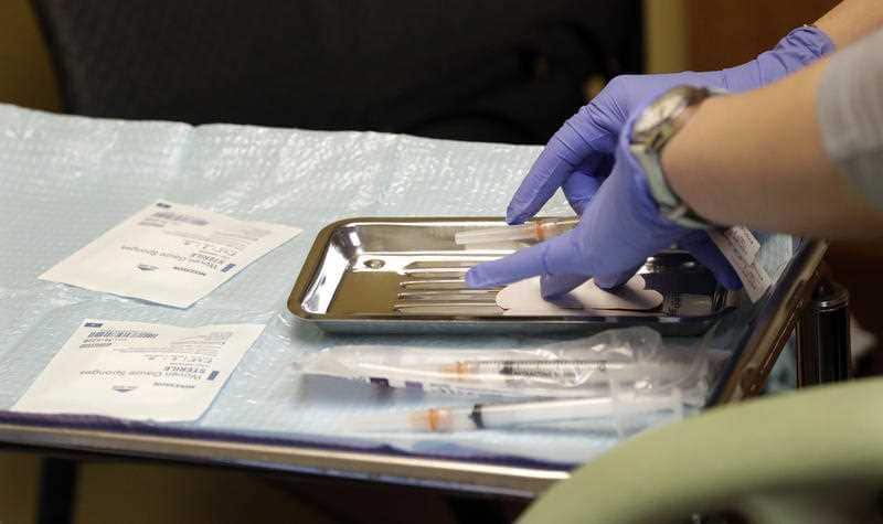 A health care worker prepares syringes, including a vaccine for measles, mumps, and rubella.