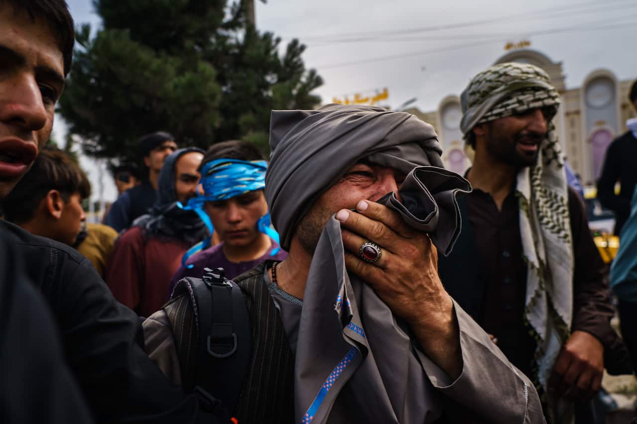 A man cries as he watches Taliban fighters conduct crowd control over thousands of Afghans who continue to wait outside the Kabul Airport.