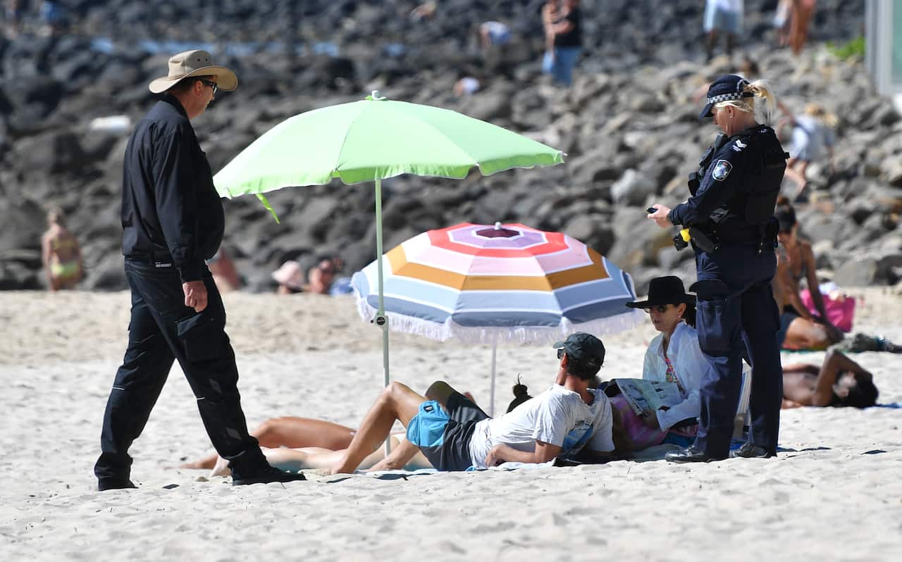 A police officer speaks to beachgoers at Burleigh Heads on Queensland's Gold Coast.