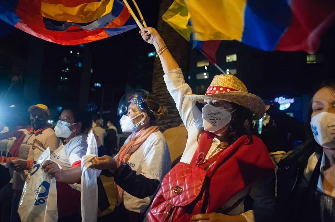 Supporters of Guillermo Lasso celebrate on a sidewalk outside Ecuador's National Electoral Council.