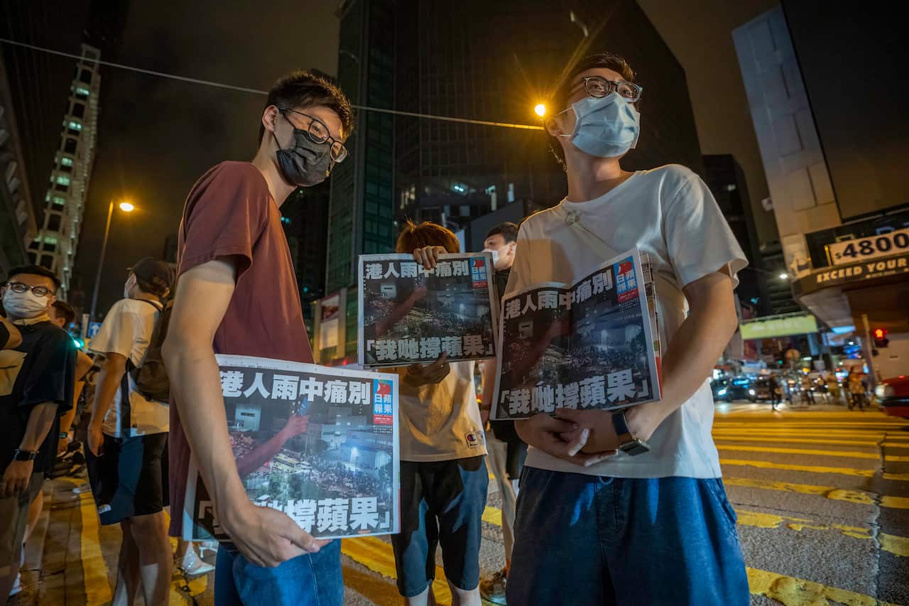 Supporters hold copies of the final edition of the Apply Daily newspaper early on 24 June.
