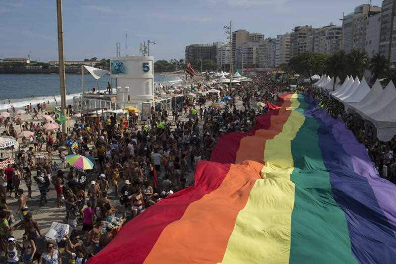 People carry a giant gay movement flag during the Gay Pride Parade at Copacabana beach in Rio de Janeiro, Brazil