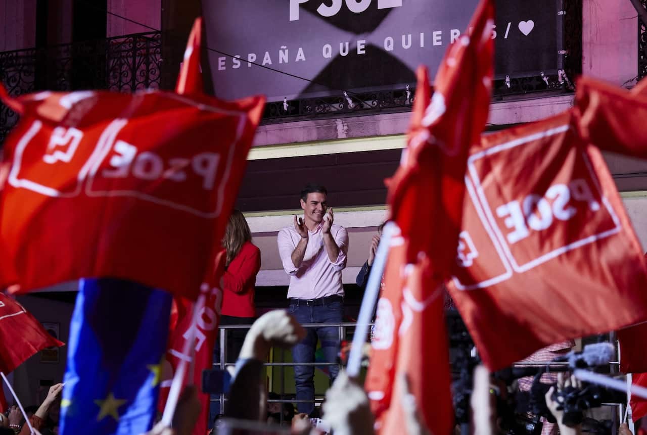 Prime Minister of Spain, Pedro Sanchez addresses supporters as they wave flags.