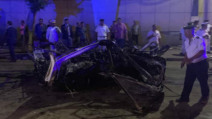People look on at the damage left by a fire from a blast at the National Cancer Institute, Cairo, Egypt
