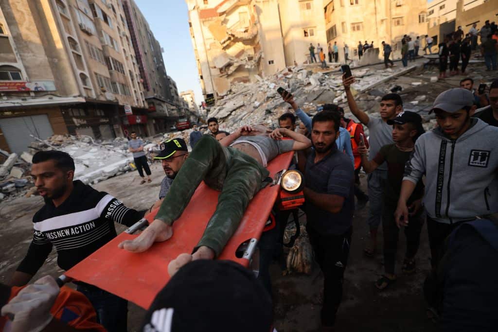 Palestinians carry a survivor found under the rubble of a building after it was struck by Israeli strikes in Gaza City, May 16, 2021