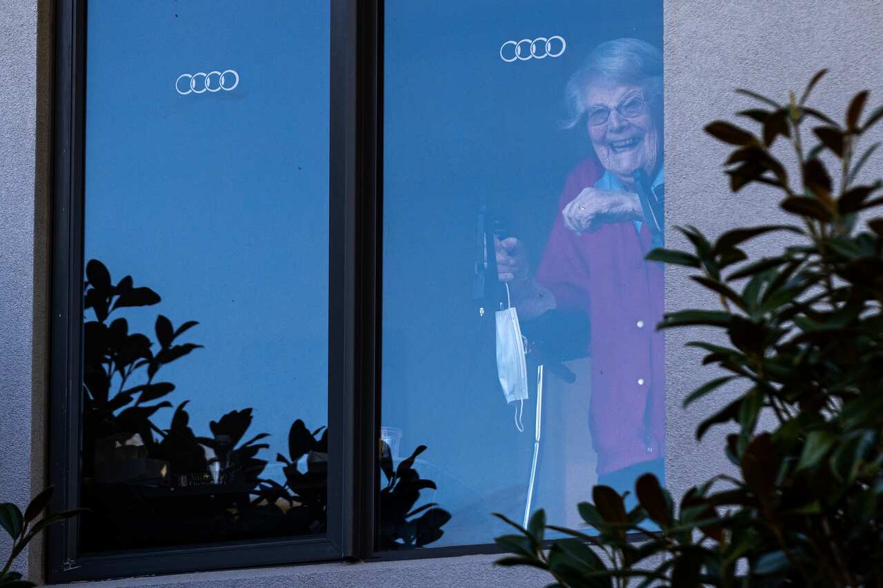 A resident at the Arcare Aged Care facility in Maidstone reacts to media from her window, in Melbourne, Monday, May 31, 2021. (AAP Image/Daniel Pockett) NO ARCHIVING