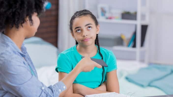 Preteen girl rolls eyes as mom takes away her phone