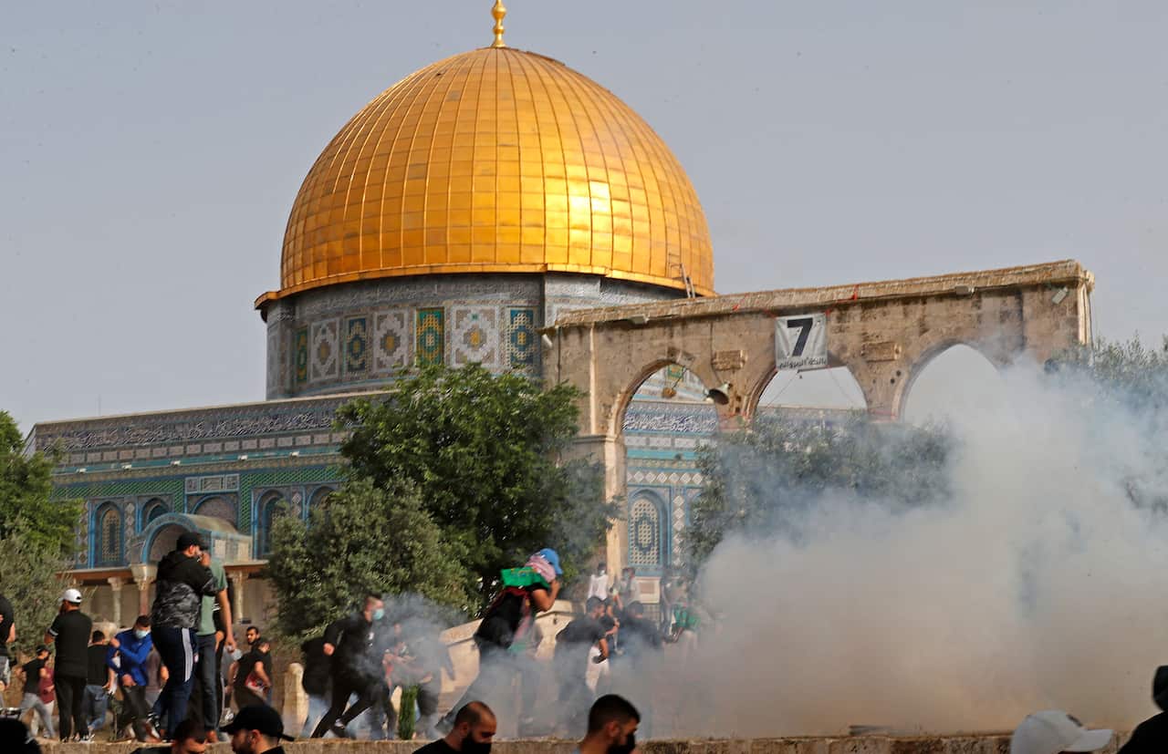 Palestinian protesters run for cover amid clashes with Israeli security forces at Jerusalem's Al-Aqsa mosque compound on 10 May, 2021.