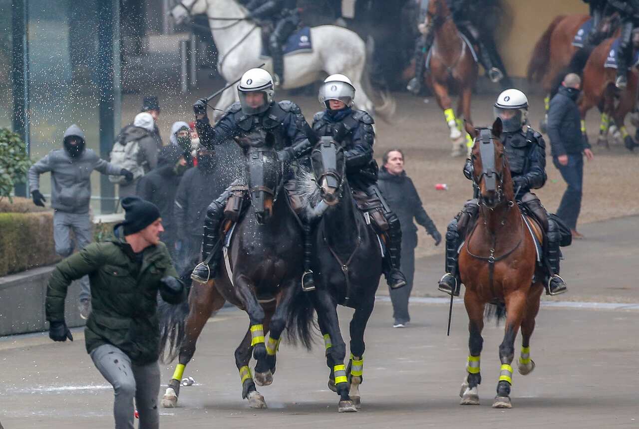 Mounted police officers chase protesters in Brussels