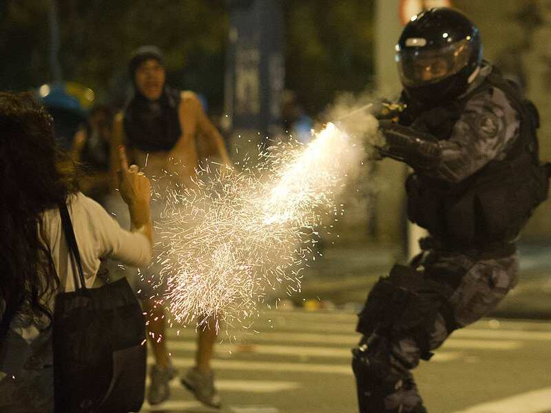 Military police from the special unit, Chope, shoots a protester with tear gas gun during clashes in the center of Niteroi.