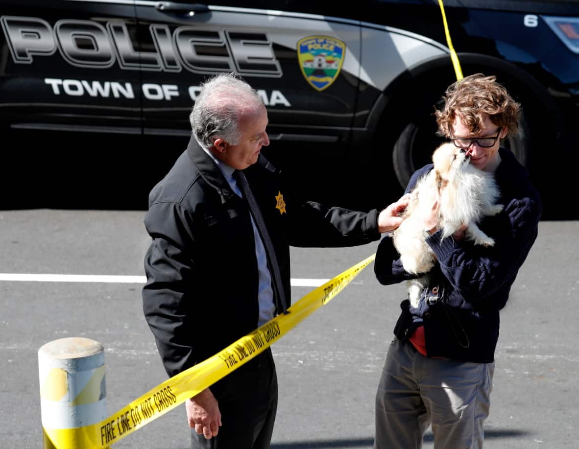 Chief of Burlingame Police Eric Wollman (L) reunites an unidentified YouTube employee with his dog, Kimba