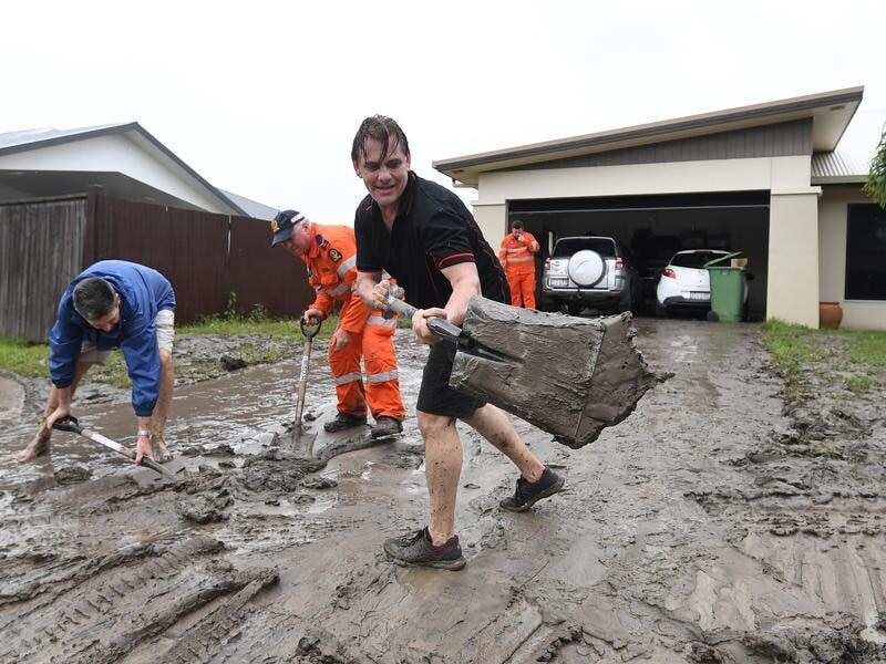 Andrew Hodgson cleans mud off his driveway in Townsville