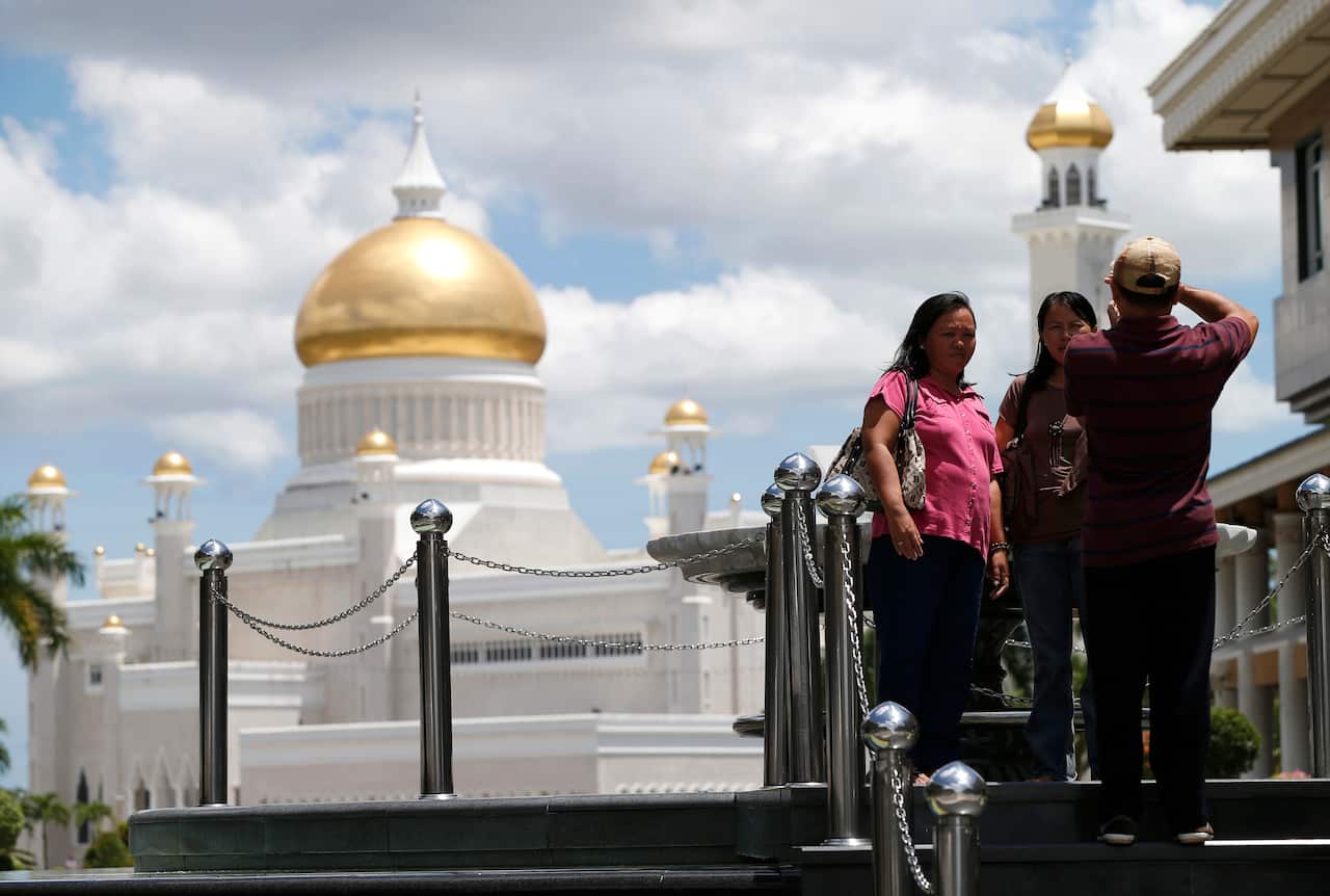 Bruneians stroll near Sultan Omar Ali Saifuddien Mosque, one of landmarks of Bandar Seri Begawan in Brunei.