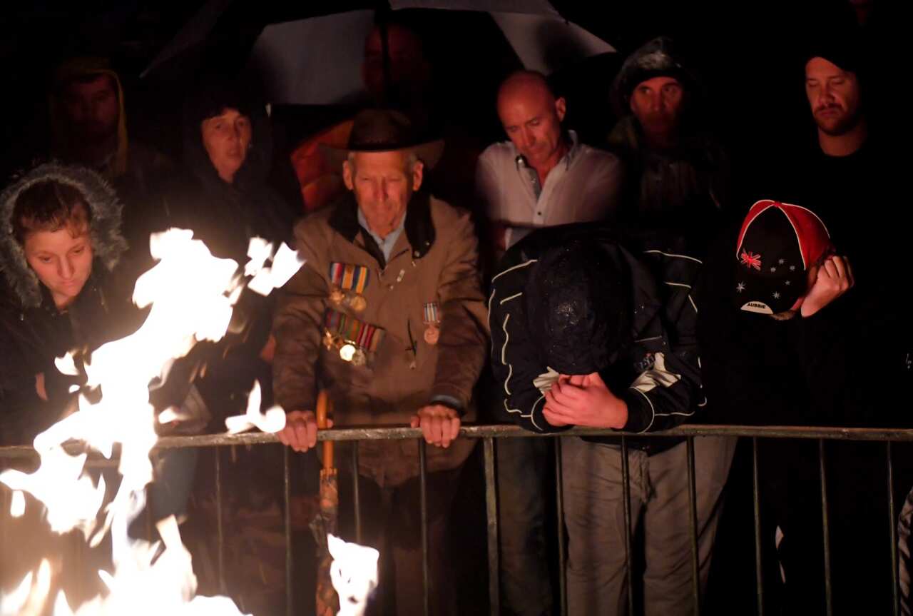 The public gather around the Eternal Flame in the rain before the Anzac Day Dawn Service during Anzac Day in Melbourne (AAP)