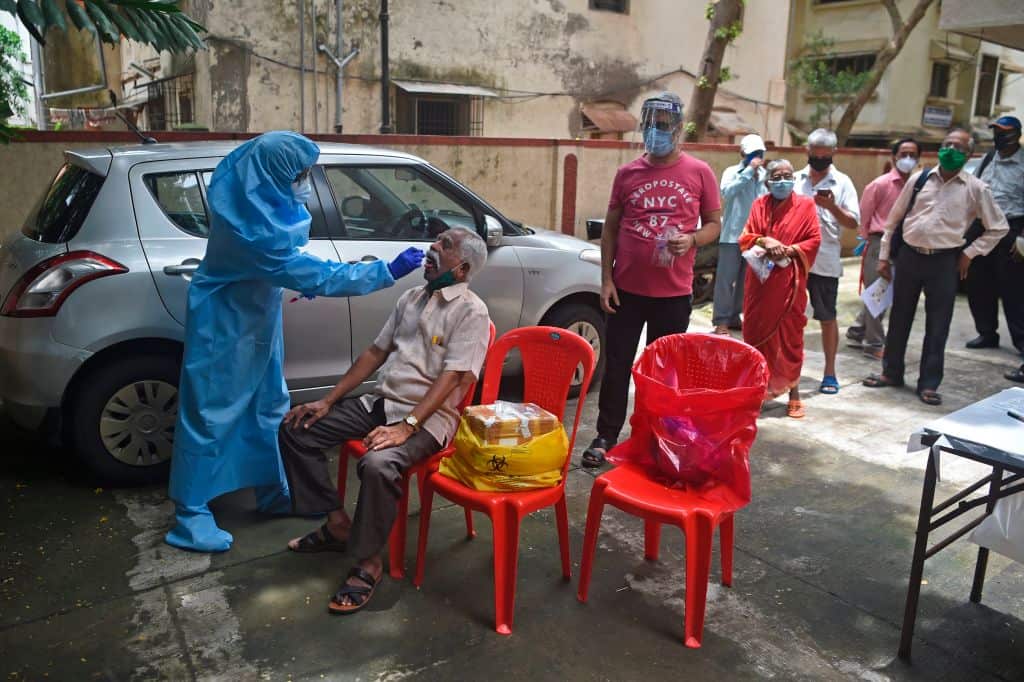 A health worker wearing Personal Protective Equipment gear collects a swab sample from a man in Mumbai