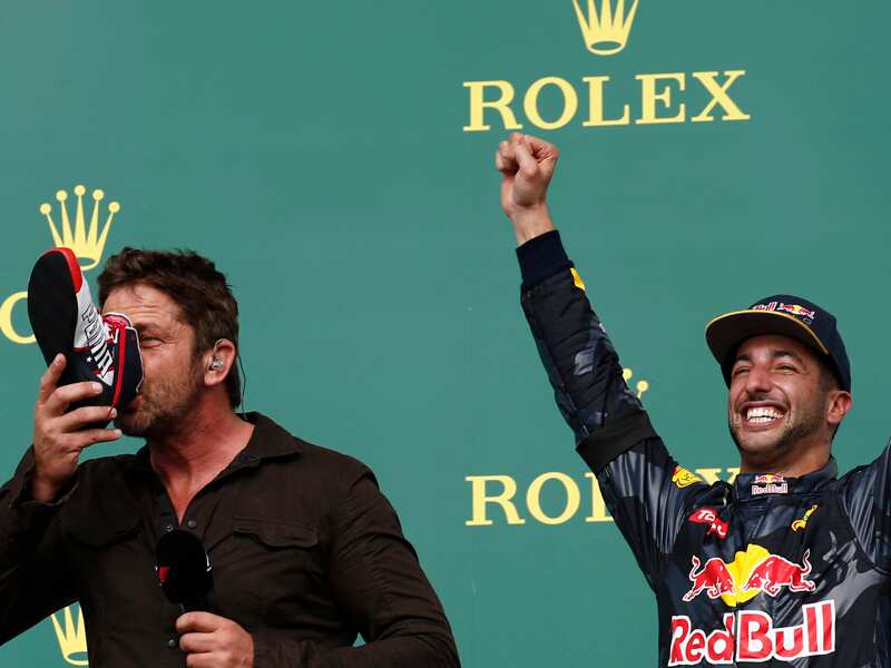 Actor Gerard Butler (L) drinks from a shoe with Daniel Ricciardo