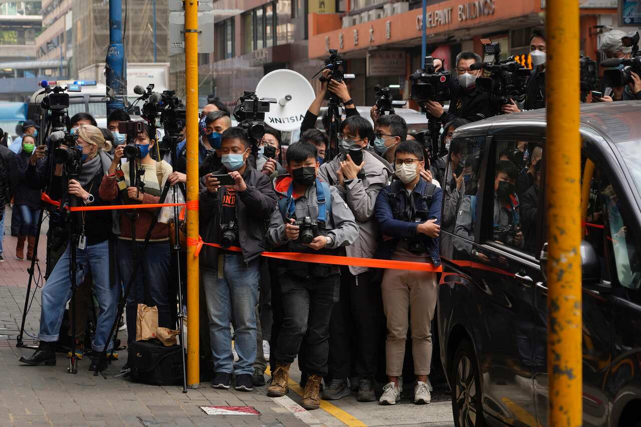 Journalists wait outside the building of the Stand News office